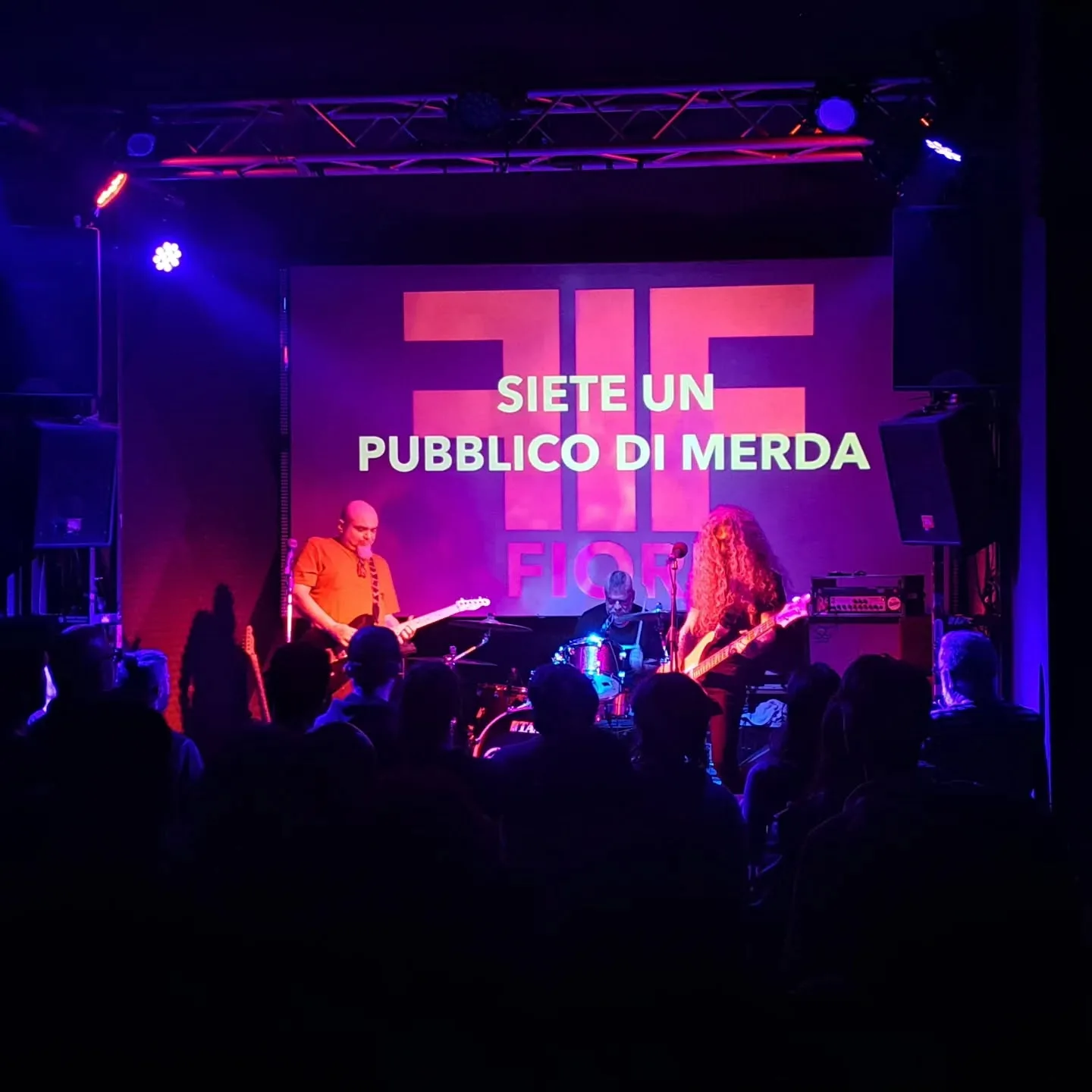 I fiori durante un concerto con la scritta dietro "siete un pubblico di merda".